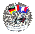 Ein auf einem weißen runden Podest, an einem Tisch arbeitenden Marienkäfer Schreibabeit am Compuer beschäftigt. Neben dem Schreibtisch ein deutlisch in Erscheinung tretender Fahnenhalter mit den Fahnen der Nationen Deutschland, Italien, Frankreich und der EU. Die Podestfront ist beschriftet mit www.coccinella.de. Eine Buntstift-Zeichnung. Rundes Bild in der Größe eines Icons.